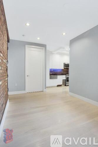 A room with a white door and a brick wall on the left side.