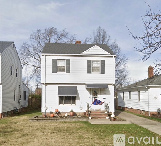 A white house with a grey roof and a flag on the front porch.