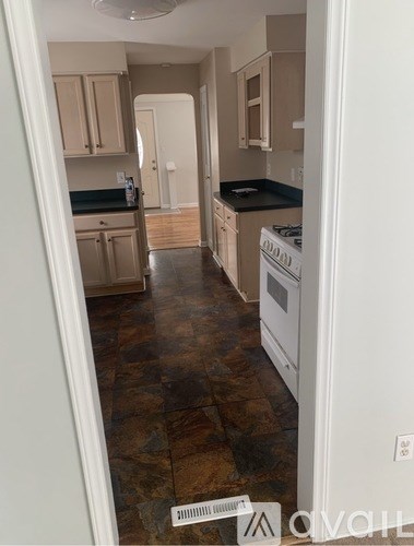 A kitchen with a white dishwasher and brown tiled floors.