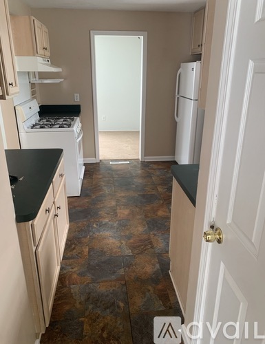 A kitchen with a white stove top oven and a white refrigerator.