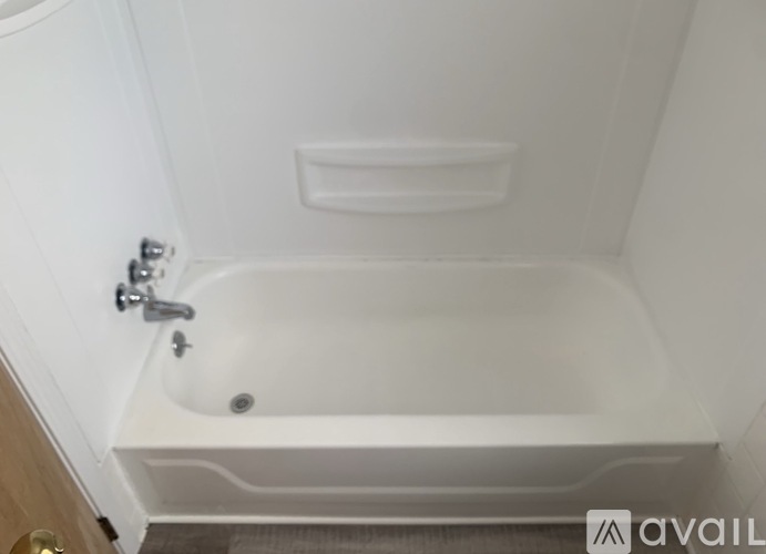 A white bathtub with a faucet and a small shelf above it.