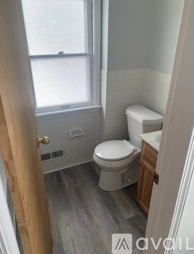 A white toilet in a bathroom with a window.