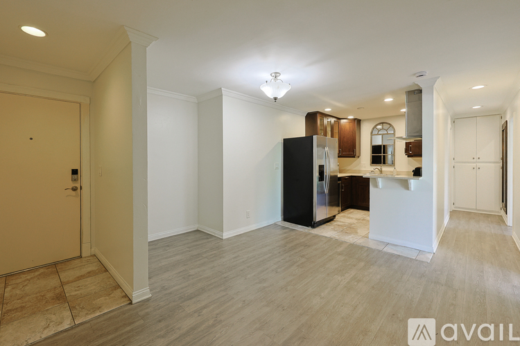A kitchen area with a black refrigerator and wooden cabinets.