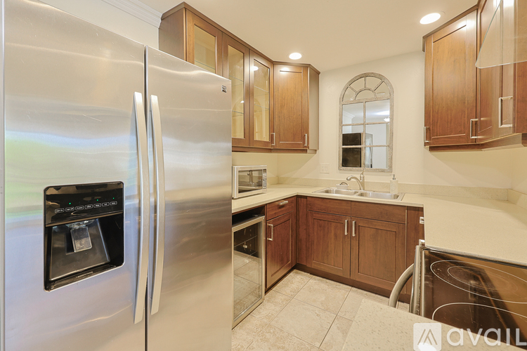 A kitchen with a stainless steel refrigerator and wooden cabinets.
