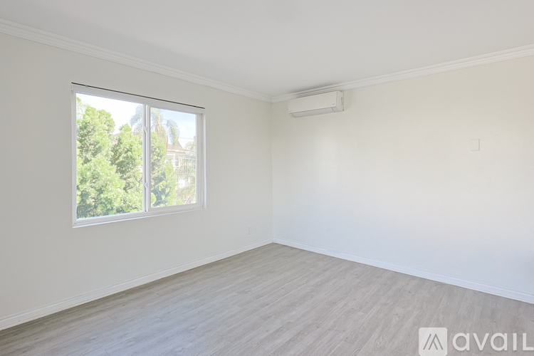 A spacious room with a window and a wall-mounted air conditioner.