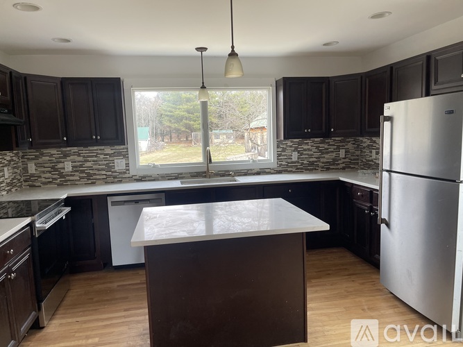 A kitchen with a large island in the middle and a refrigerator on the right.