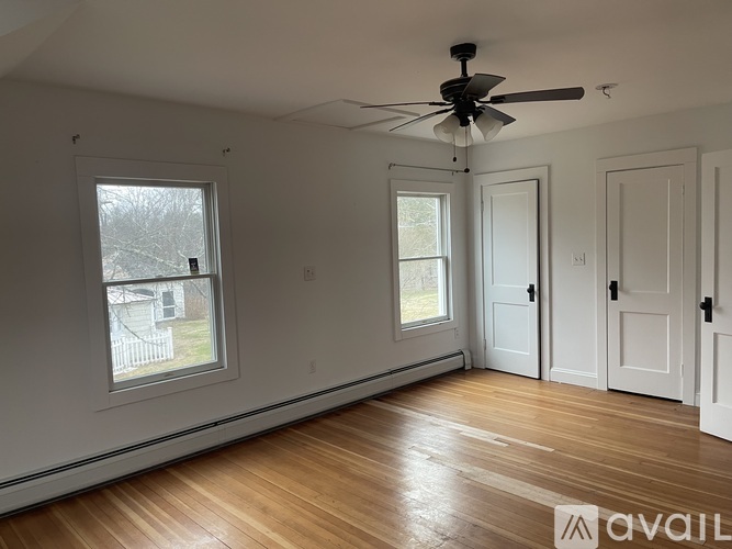 A room with a ceiling fan and wooden floors.