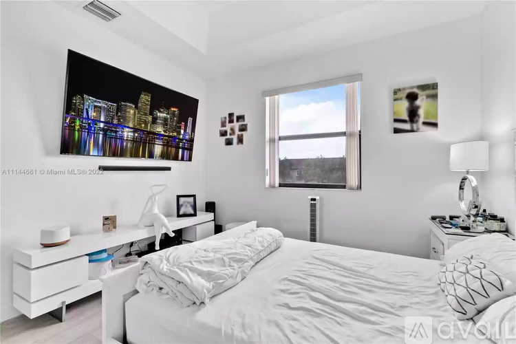 A bedroom with a large bed, a nightstand with a lamp, and a painting on the wall.