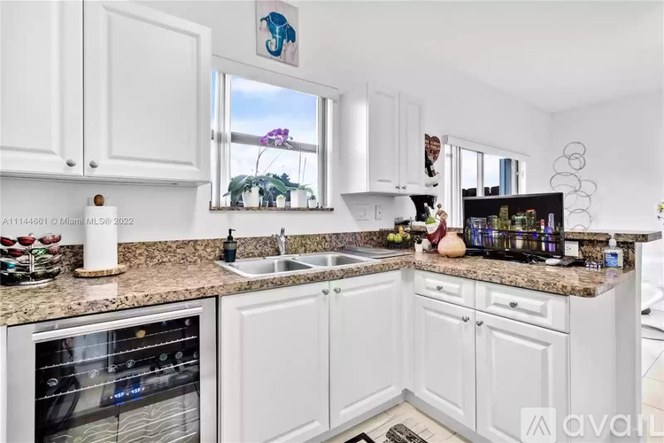A kitchen with white cabinets and granite countertops.