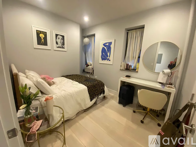 A bedroom with a bed, desk, chair, and a mirror.