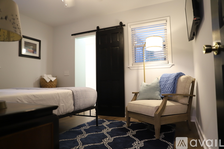 A bedroom with a bed, chair, and a window with blinds.