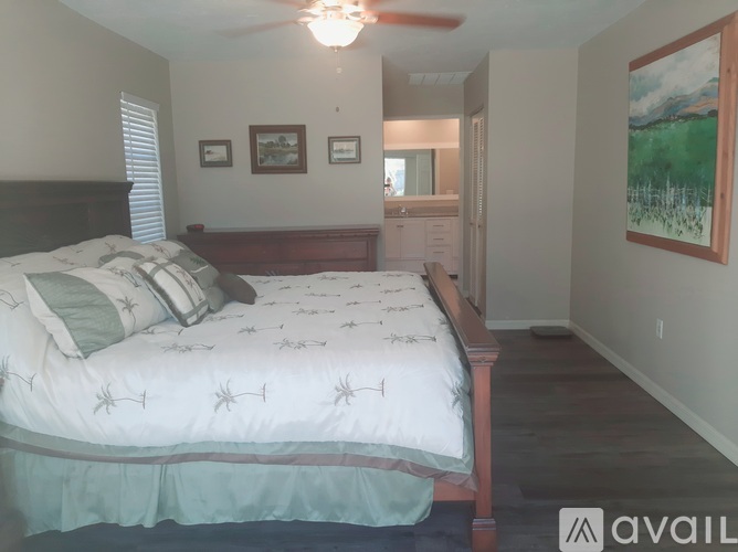 A bedroom with a bed, dresser, and painting on the wall.
