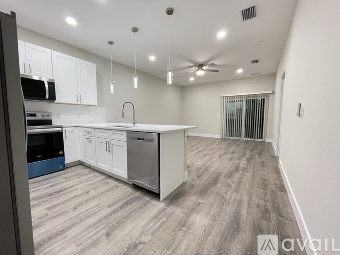 A modern kitchen with white cabinets and a wooden floor.