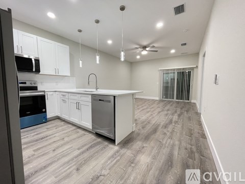 A modern kitchen with white cabinets and a wooden floor.