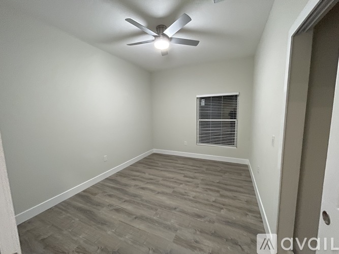 A room with a ceiling fan and a window with blinds.