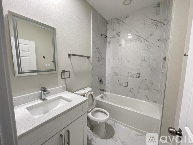A bathroom with a marble tile shower and a white toilet.