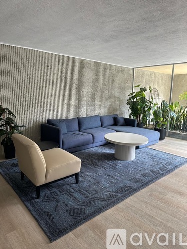 A living room with a blue couch, a white chair, and a round table.