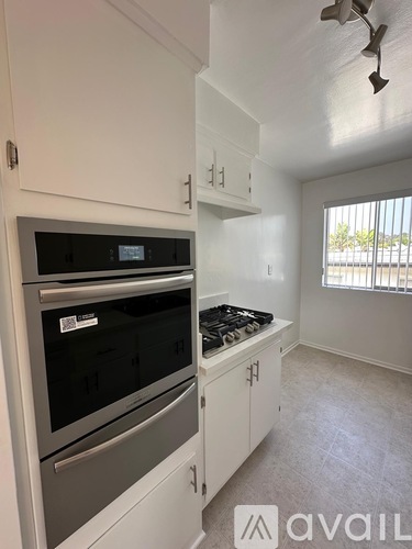 A kitchen with white cabinets and a black microwave.