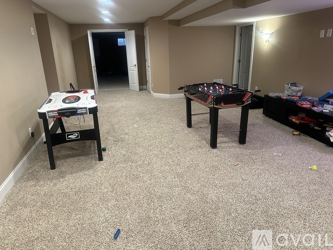 A room with a carpeted floor, a pool table, and a foosball table.