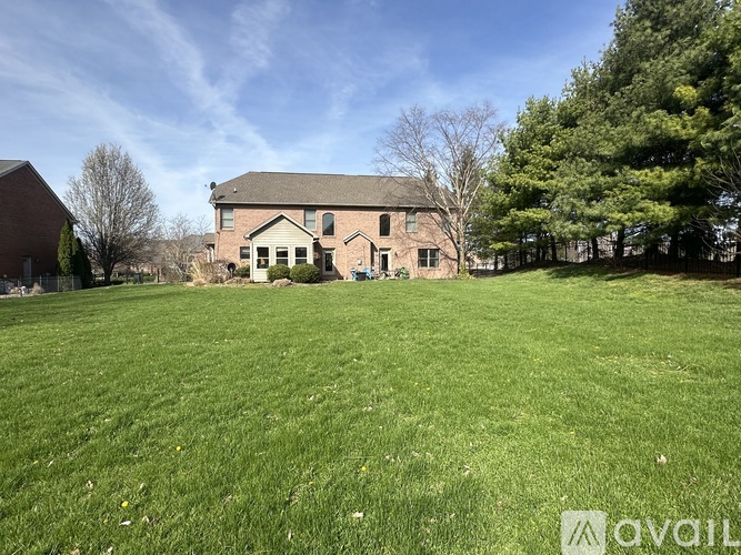 A large grassy field with a house and trees in the background.