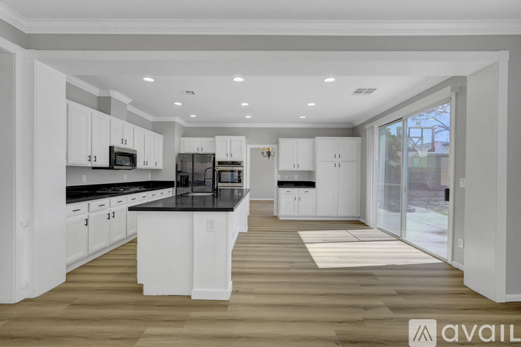 A modern kitchen with white cabinets and black countertops.
