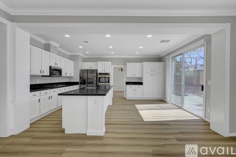 A modern kitchen with white cabinets and black countertops.