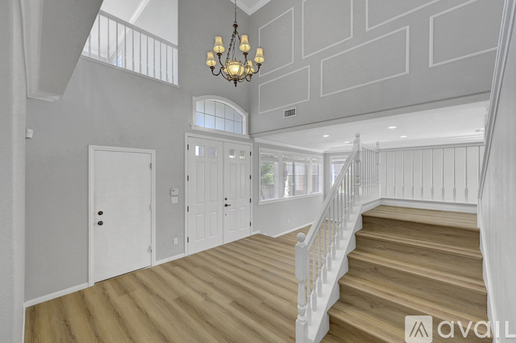 A chandelier hangs over a staircase in a spacious home.