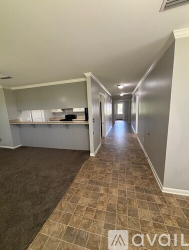 A long hallway with a kitchen area on the left and a doorway leading to another room on the right.