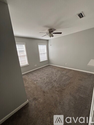 A room with a ceiling fan and carpeted floor.