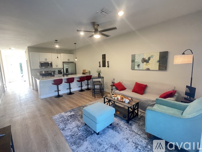 A living room with a white couch, a blue chair, and a rug.