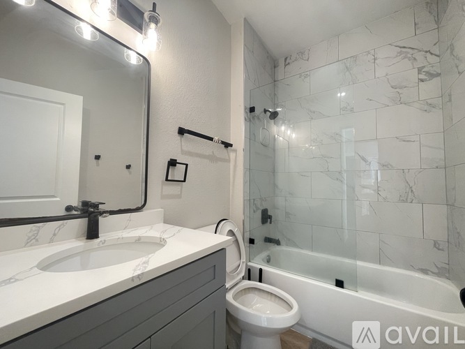 A bathroom with a marble tile shower and a white toilet.