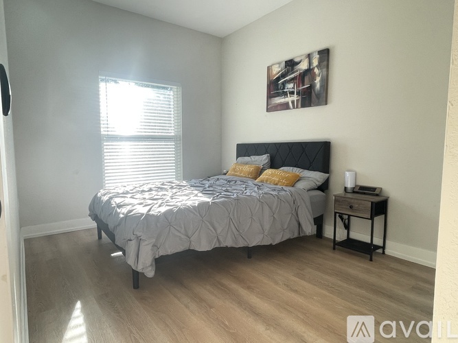 A bedroom with a bed, nightstand, and a painting on the wall.
