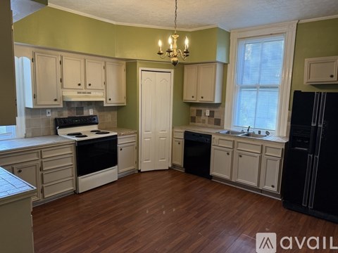 A kitchen with wooden floors and white cabinets.