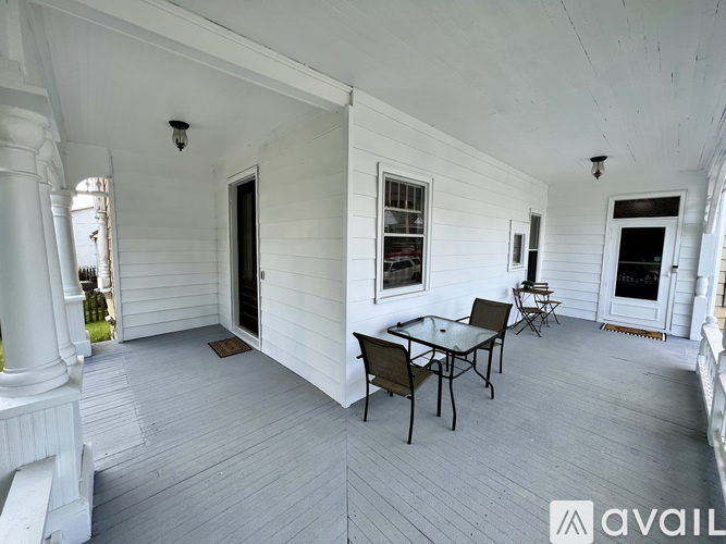A white porch with a table and chairs.