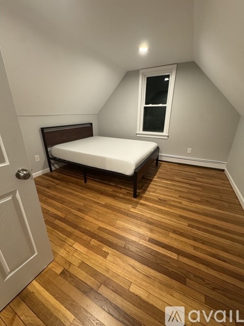 A bedroom with a bed and wooden floors.