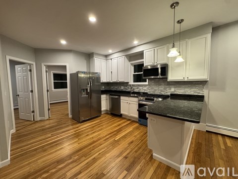 A kitchen with wooden floors and a black countertop.