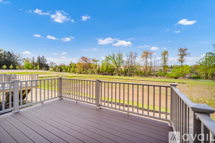 A wooden deck with a metal railing overlooks a grassy area with trees.