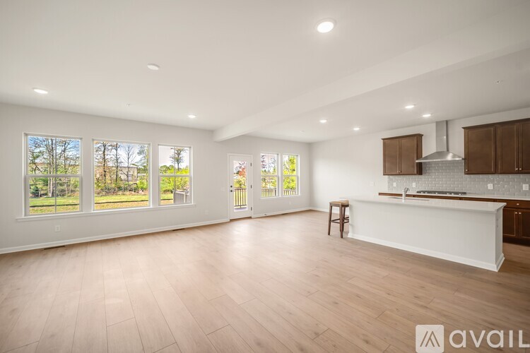 A spacious kitchen and living room with wooden floors and large windows.