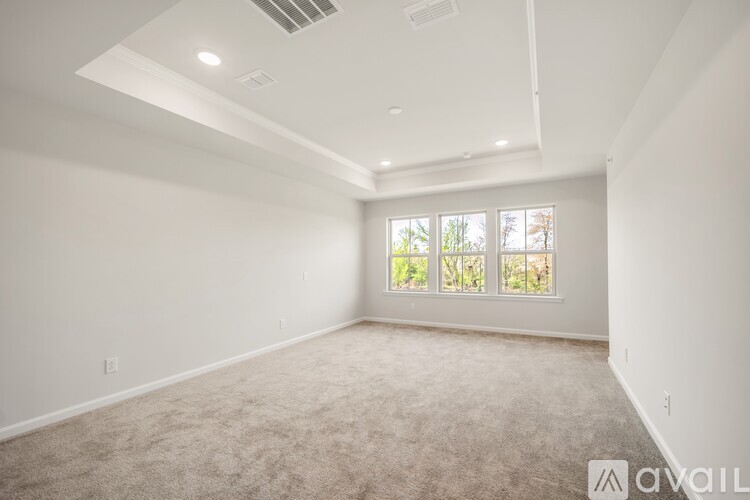 A spacious room with a carpeted floor and a window with a view of trees outside.