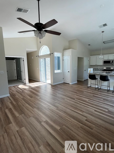 A spacious room with a ceiling fan and hardwood flooring.