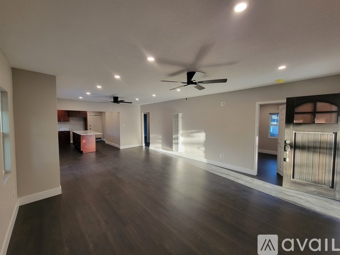A spacious room with a ceiling fan and wooden flooring.