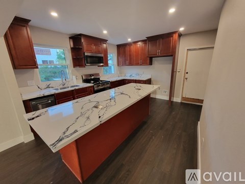A kitchen with a marble countertop and wooden cabinets.