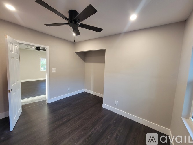 A room with a ceiling fan and wooden flooring.