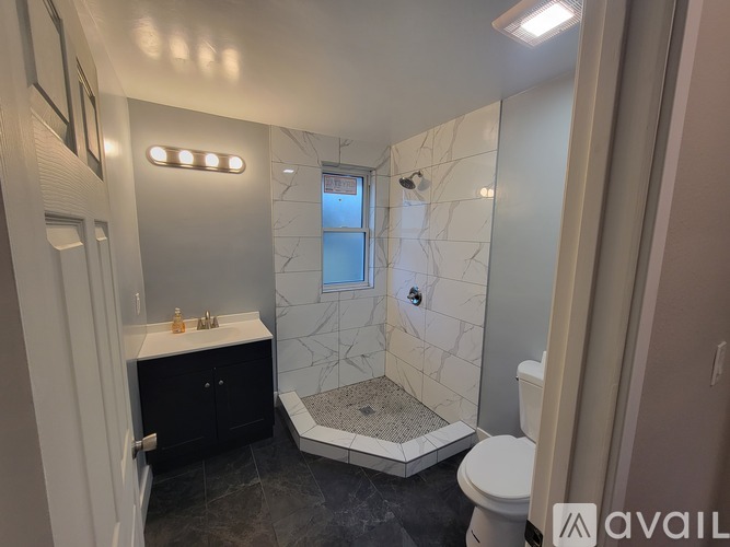 A bathroom with a marble shower and a toilet.