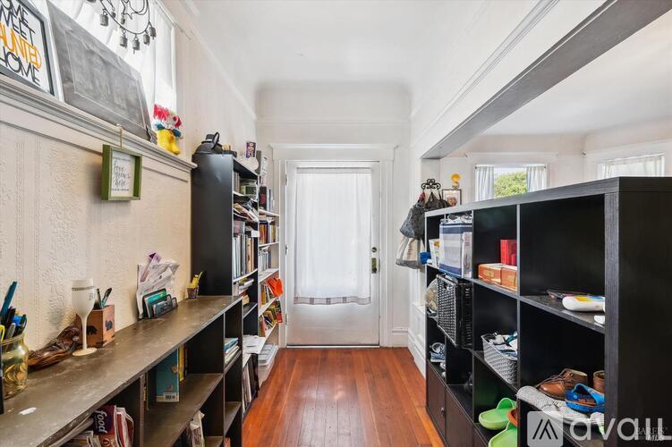 A hallway with a white door and a black bookshelf on the right.