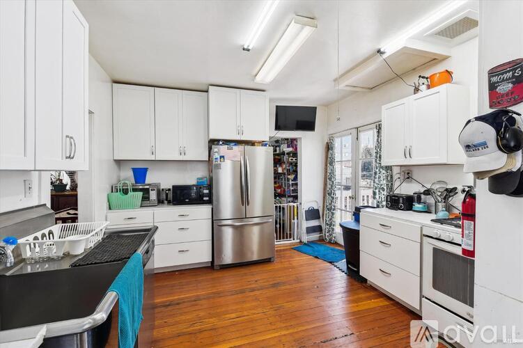 A kitchen with white cabinets and a wooden floor.