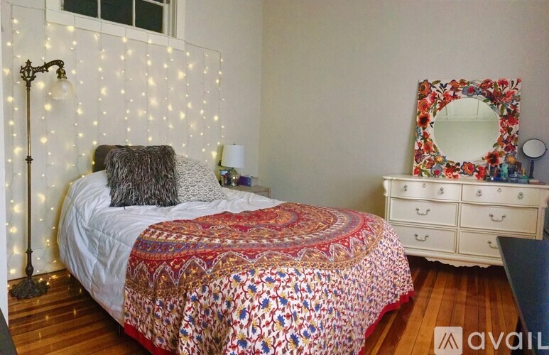 A bedroom with a bed, a mirror, and a dresser.