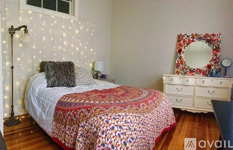 A bedroom with a bed, a mirror, and a dresser.