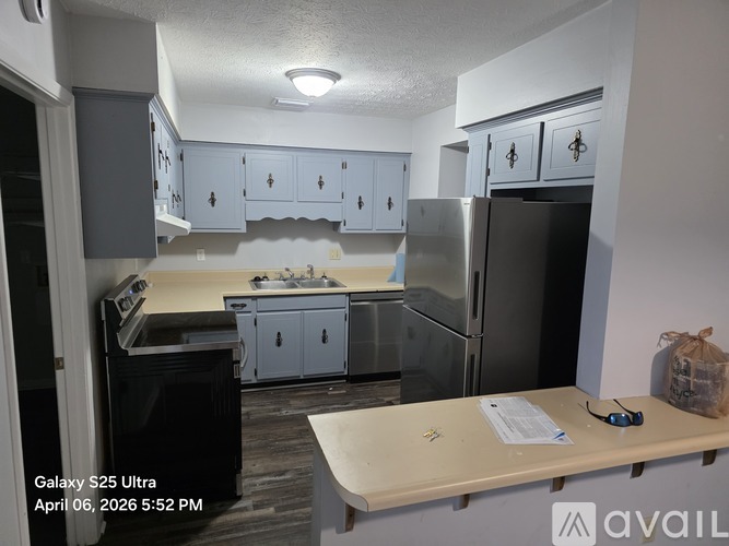 A kitchen with a black fridge and white cabinets.