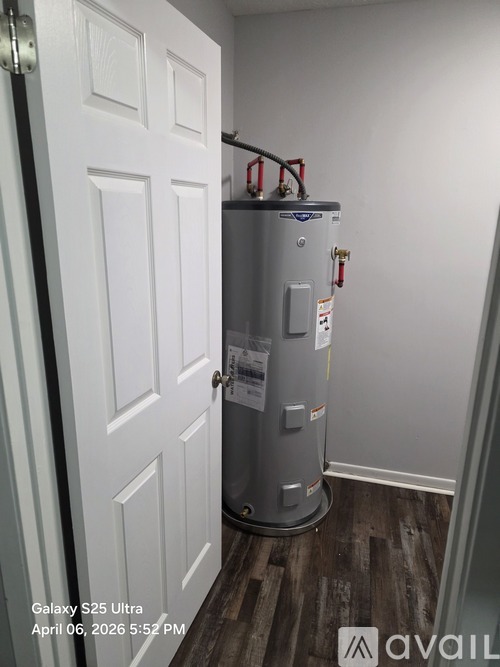 A tall, silver water heater is installed in a white doorway.